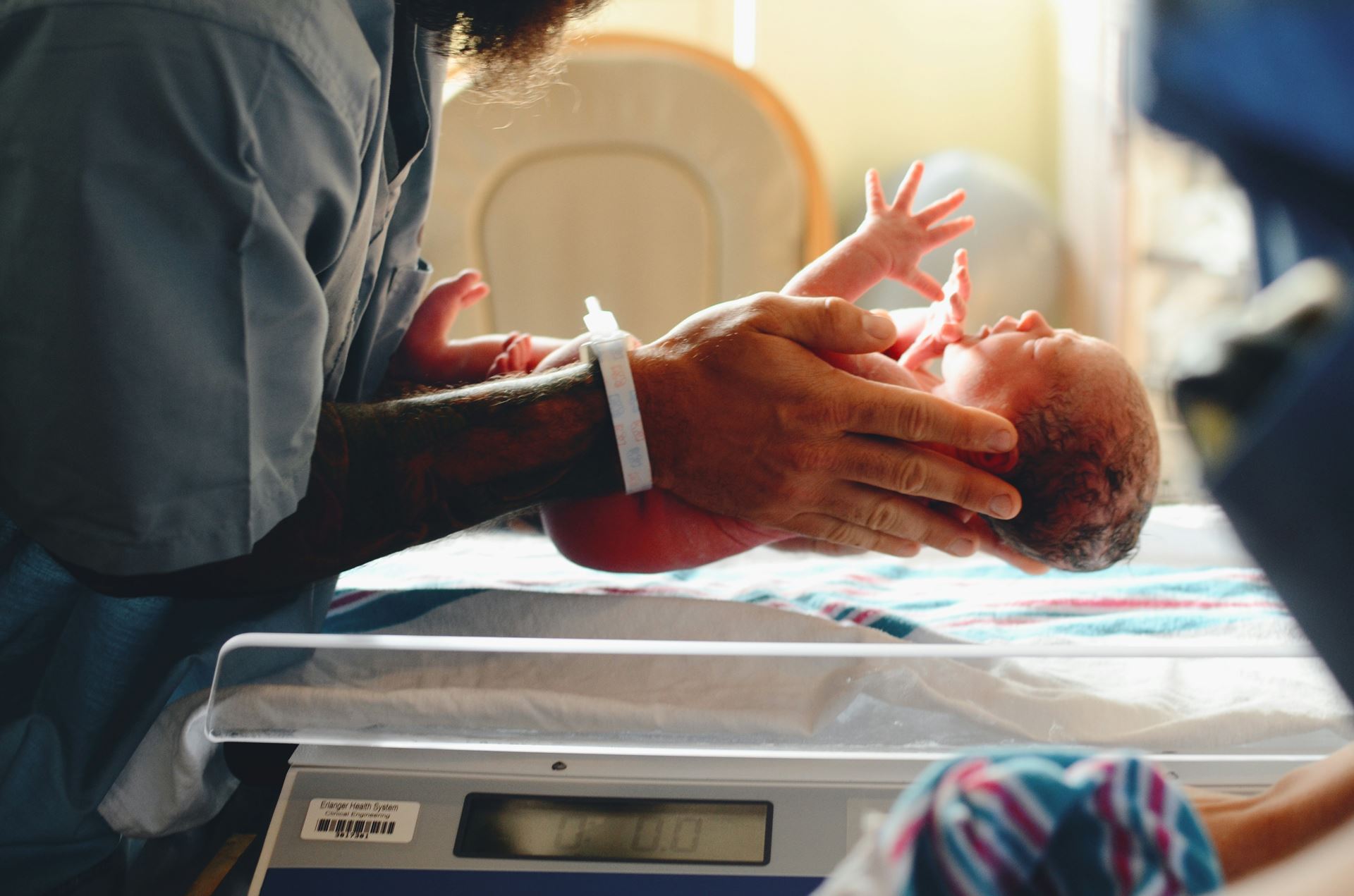 someone holding a baby above weighing scales 